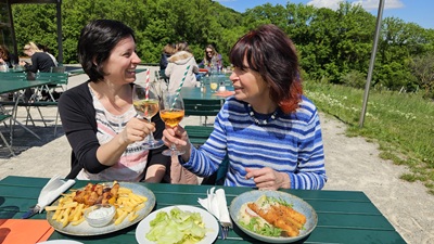Mutter mit Tochter und Essen beim Anstoßen im Gastgarten beim Oktogon am Himmel.