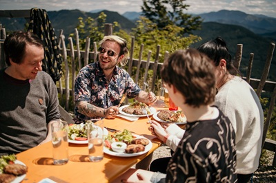 Zwei Männer und zwei Frauen essen auf der Anna-Alm Kasspressknödel und Fleischlaberl.