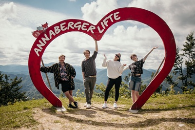 Zwei Männer und zwei Frauen posieren für ein Foto auf der Bergstation der Annaberger Lifte unter dem roten Holzherz.