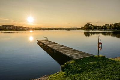 Der Badesee Rauchwart bei Sonnenuntergang mit Steg und Schwimmreifen im Vordergrund