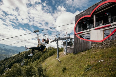 Frau und Mann fliegen hintereinander bei der Zipline Annaberg