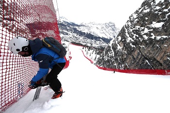 Skipiste in Cortina, Italien, Pistenarbeiter fixiert den Zaun auf steilem Hang