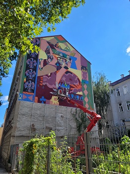 Street Art Künstler auf Kran bemalt Feuermauer in Wien