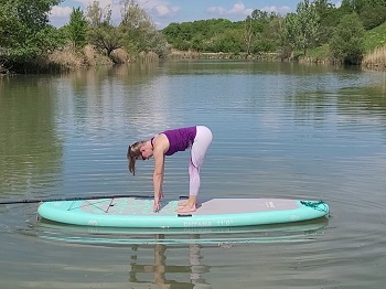 Yogalehrerin in halber Vorbeuge am Stand Up Paddling Board