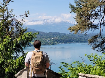 Mann mit Rucksack blickt von einem Aussichtspunkt auf dem Wörthersee Rundwanderweg