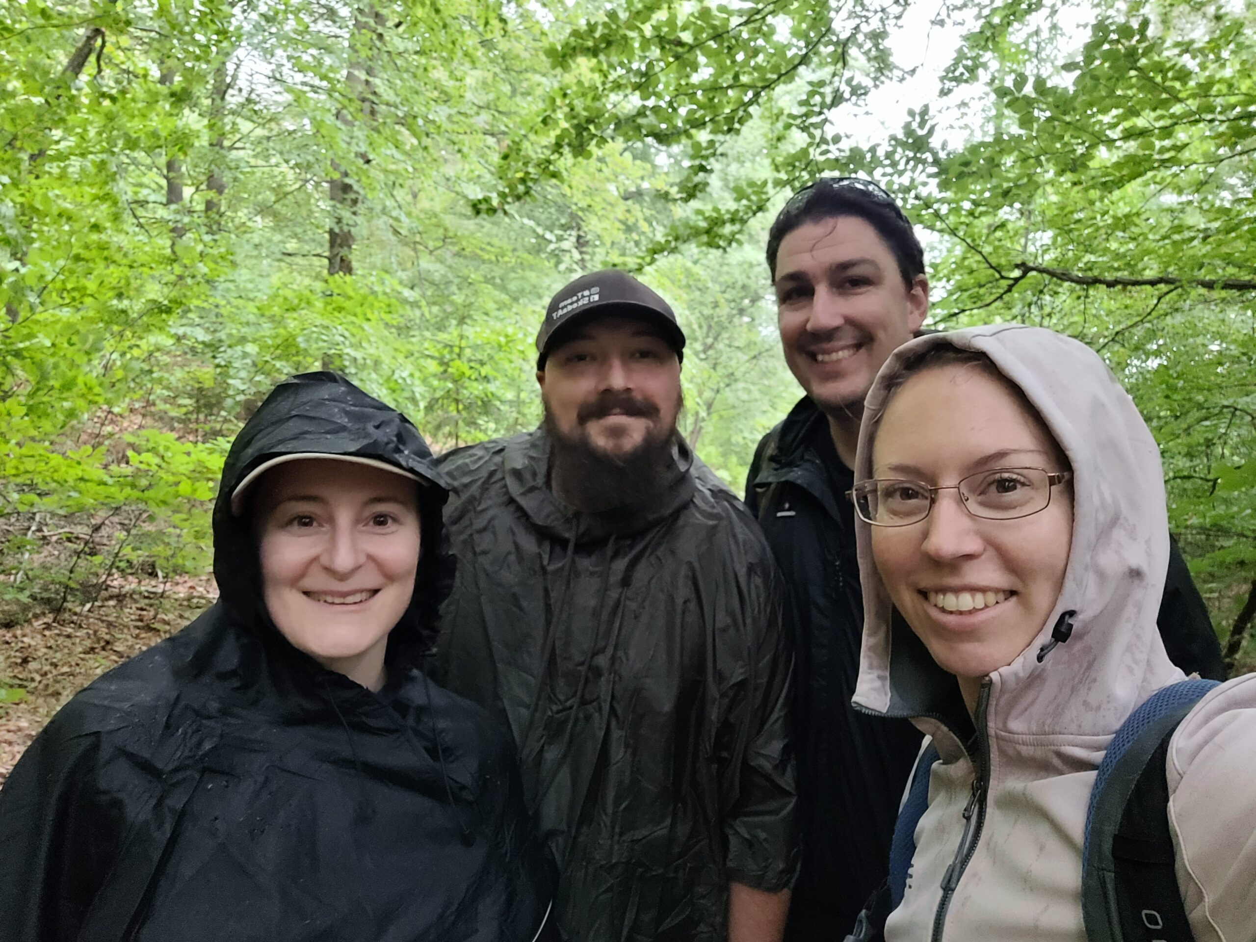 Zwei Pärchen in Regenmontur im Wald