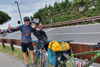 Ende des Alpe Adria Radwegs, zwei Radfahrer vor der Ortstafel in Grado