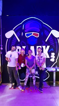 Drei Männer und eine Frau mit Neonbemalung und 3D Brillen vor ihrem ersten Blacklight Minigolf Spiel