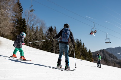 Kind hält sich bei Papas Skistecken fest im Skigebiet Annaberg