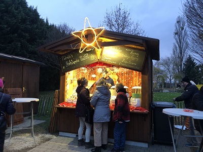 Drei Personen vor einem Essensstandl beim Weihnachtsmarkt Hirschstetten
