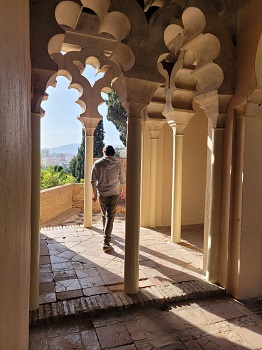 Mann spaziert durch die Säulen des Alcazaba Málaga