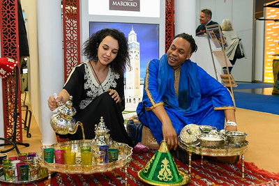 Frau und Mann schenken bei der Ferienmesse Wien marokkanischen Tee aus