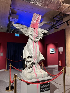 Banksy Skulptur - einer Engelsstatue ist ein pinker Farbtopf über den Kopf gestülpt.