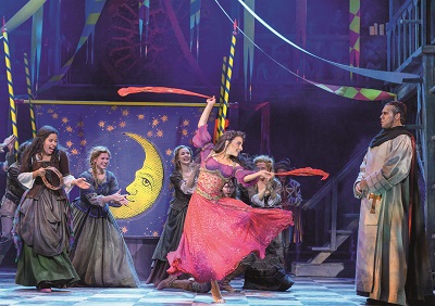 Esmeralda tanzt auf der Musicalbühne des Glöckners von Notre Dame in einer Marktszene und trägt ein pinkes Kleid