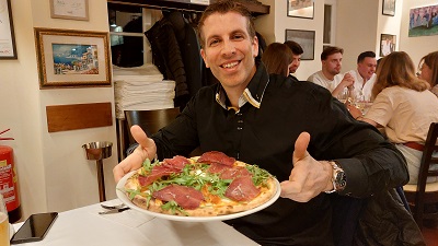 Mann mit Pizza am Tisch in der Il Mare