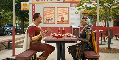 Zachary Levi als Shazam und Helen Mirren als Hespera beim Verhandeln am Tisch.