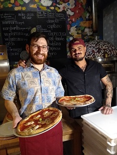 Pizzabäcker mit Bio-Pizza vor dem Ofen in der Pizzeria Vero