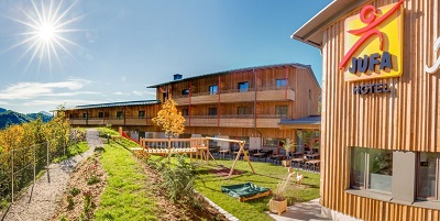 Das JUFA Hotel Annaberg von außen mit Blick auf den Garten, Spielbereich und die Essensterasse