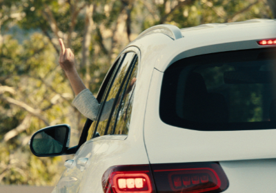 Ali Wong als Amy in Episode 1 von der Netflix-Serie Beef. Man sieht nur ihre Hand. Sie zeigt den Mittelfinger durch das Fenster ihres weißen Autos.