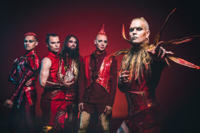 Die Band Lord of the Lost posiert vor einem roten Hintergrund.