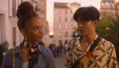 Eine Szene aus der zweiten Staffel Heartstopper. Elle und Tao gehen nah bei einander eine Straße in Paris entlang.