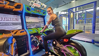 Frau sitzt auf dem Bike eines Moto GP Automaten in der Playworld