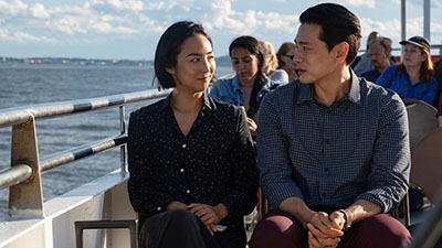 Teo Yoo als Hae Sung und Greta Lee als Nora auf einem Boot im Hafen New York Citys.