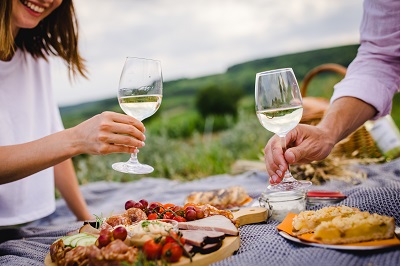 Zünftige Jause, Dessert und zwei Weingläser vor dem Anstoßen auf einer Picknickdecke in Mailberg im Weinviertel