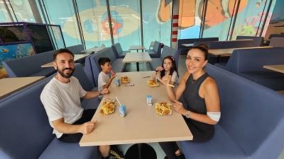Familie sitzt in der Playworld an einem Tisch und isst Chicken Nuggets und Pommes