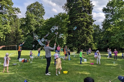 Kinder mit ein paar Eltern beim Seifenblasen-Machen im Garten vor dem Europahaus in Wien bei einem Workshop von Dr. Bubbles