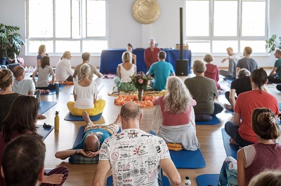 Teilnehmer und Teacher sitzen in großem Saal bei Bliss Festival Retreat