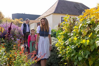 Familie mit Frau Mann und Kind in Tracht in einem Garten im Museumsdorf Niedersulz
