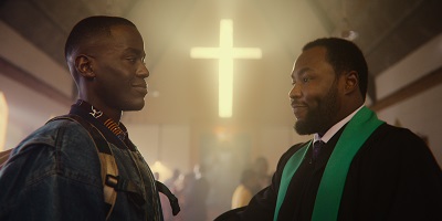 Eric mit dem Pastor seiner Kirche vor einem Kreuz