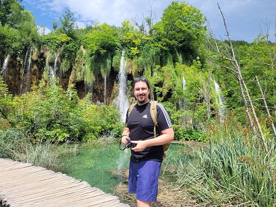 Mann mit Kamera vor Wasserfall