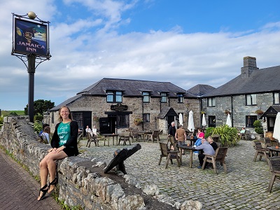 Frau auf Steinmauer sitzend vor dem Jamaica Inn in Cornwall