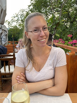 Lächelnde Frau in Gastgarten mit Weinglas