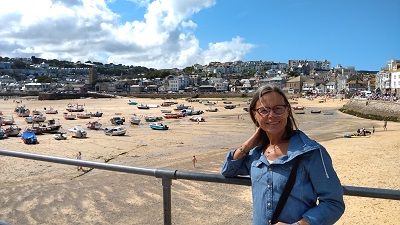 Lächelnde Frau vor Hafen mit Booten auf Sand auf Cornwall Rundreise