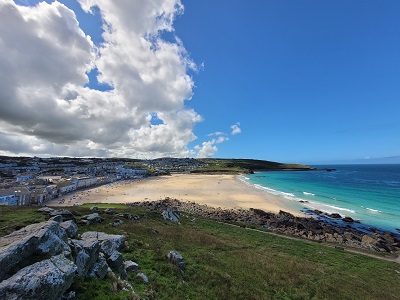 Blick über grünen Hügel auf hellen Sandstrand