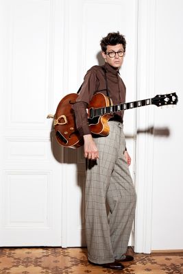 Norbert Schneider mit Brille und Gitarre in der Hand