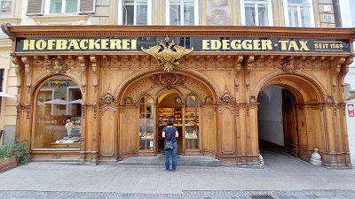 Frau vor der Holzfassade der Hofbäckerei Edegger-Tax in der Grazer Altstadt