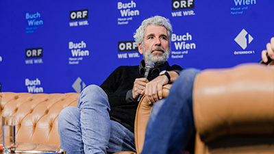 Dirk Stermann sitzt auf einer Bühne bei der Buch Wien