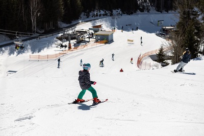 Kind fährt auf der Piste in Annaberg im Schneepflug, im Hintergrund ist die Talstation