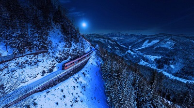 Mondscheinfahrt der Mariazellerbahn, der Zug der Himmelstreppe fährt dem Berg entlang durch Wald und Winterlandschaften