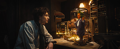 Timothée Chalamet als Willy Wonka, Hugh Grant als Oompa Loompa im Glas.