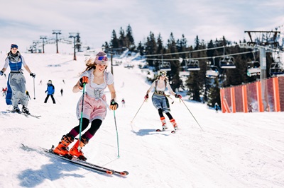 Skifahrerinnen wedeln im Dirndl den Hang hinunter beim Trachtenskitag am Hochkar