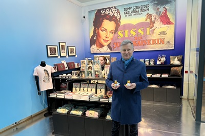 Mann steht mit Sissi Badeenten in der Hand vor einem Sissi Merchandising Stand im Theatermuseum