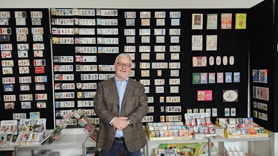 Ferdinand Piatniks Ur-Ur-Enkel Dieter Strehl vor einer Wand mit Piatnik Karten
