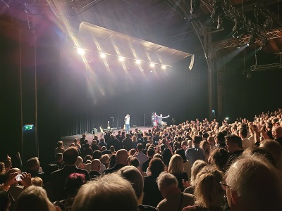 Stehendes Publikum im vollen Globe Wien bei der Lotterbuben Premiere, Viktor Gernot und Thomas Stipsits auf der Bühne