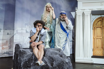 Jenny Frankl, Michael Niavarani und Matthias Mamedof im Götterkostüm mit Feldstecher an einem Felsen auf der Bühne im Theater im Park