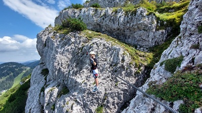 Teenager steht auf der Seilbrücke am Heli Kraft Klettersteig und schaut in die Ferne.